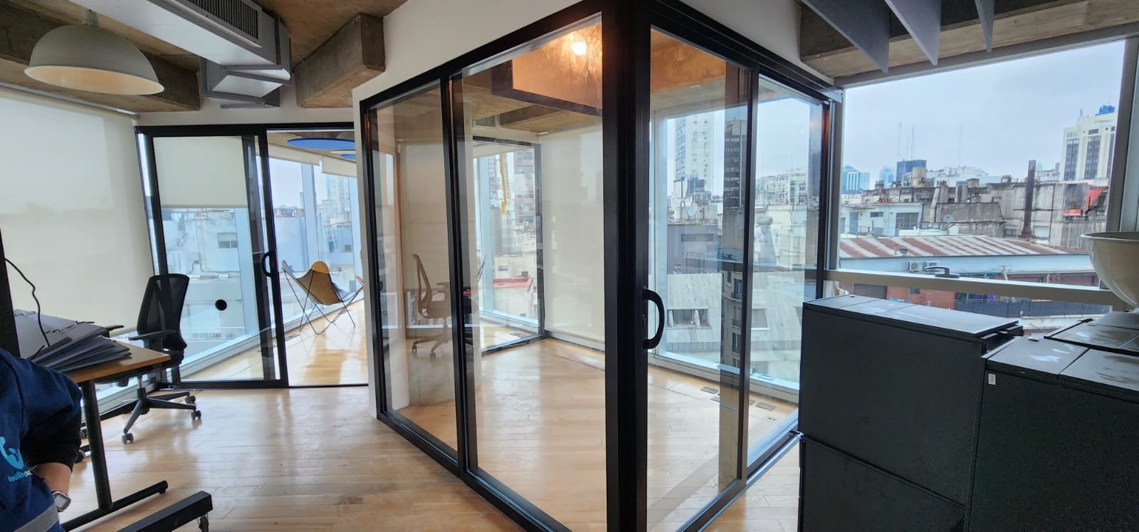Escritório moderno com divisória de vidro e vista urbana — projeto Oficinas en IBM o Frente integral negro, por Cristalcenter, em Puerto Madero